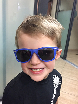 Child smiling with sunglasses. Sun Safety - Too much exposure can be harmful for the eyes. Wear sunglasses.