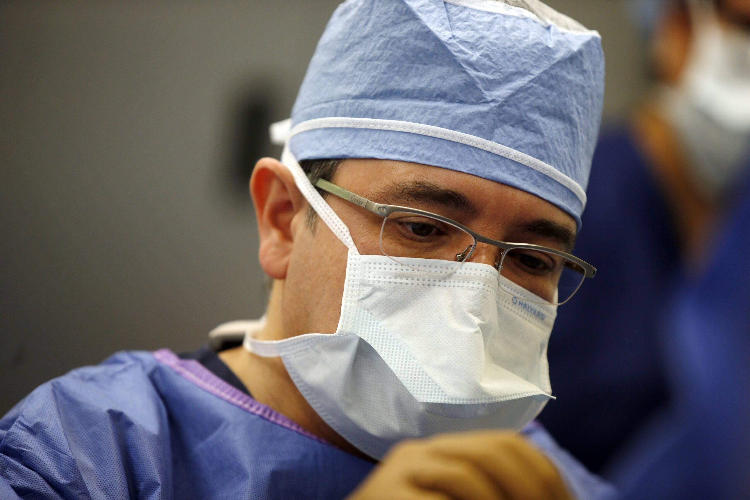 Dr. Abrams in scrubs and with a mask performing surgery