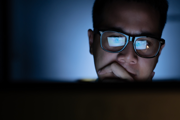 A focused and serious looking man working and thinking hard on a computer stock photo