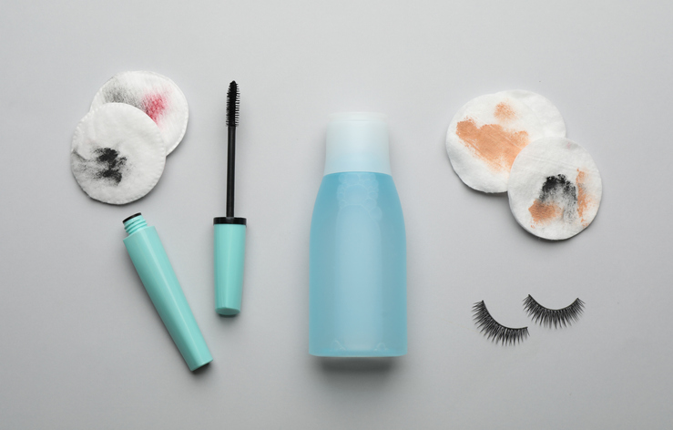 Dirty cotton pads, eyelashes, mascara and makeup removal product on light grey background, flat lay stock photo